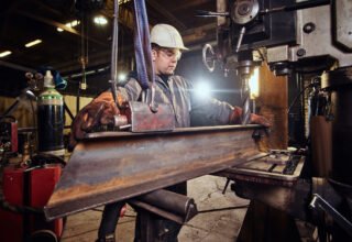 Man in helmet is moving a piece of rail at metal factory. Man in helmet is moving a piece of rail at metal factory.