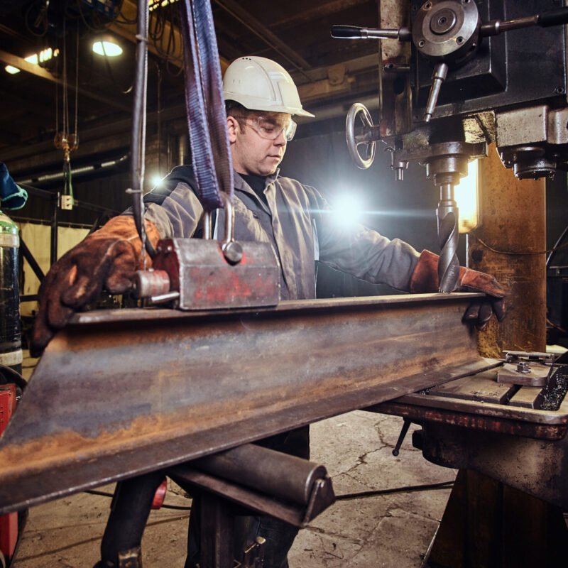 Man in helmet is moving a piece of rail at metal factory. Man in helmet is moving a piece of rail at metal factory.